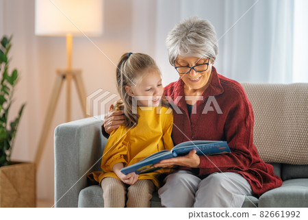Grandmother reading a book to granddaughter. Grandmother reading a book to granddaughter. 82661992