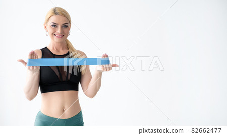Fitness equipment. Sportive woman. Presenting product. Advertising background. Happy fit lady showing rubber bend in hands for workout isolated white copy space. Fitness equipment. Sportive woman. Presenting product. Advertising background. Happy fit lady showing rubber bend in hands for workout isolated white copy space. 82662477