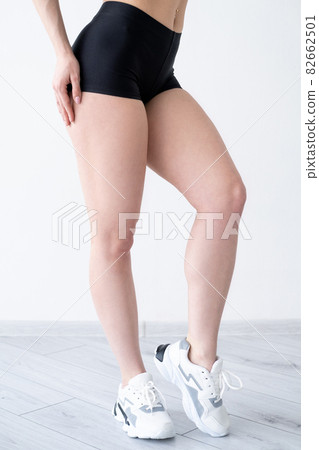 Fitness model. Athletic woman. Perfect body. Sportive cloth. Beautiful slim lady posing in stylish black sport shorts showing elegant legs isolated white. 82662501