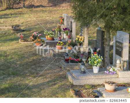 Hermanice v Podjestedi, Czech Republic, April 4, 2021: stone graves at country cemetery at small village in Lusatian Mountains, decorated by flowers and lanterns 82663445