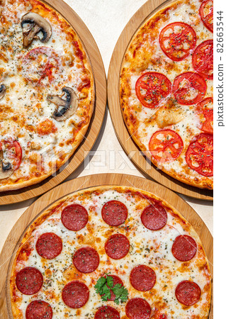 Delicious italian pizzas served on wooden table. Delicious italian pizzas served on wooden table. 82663544