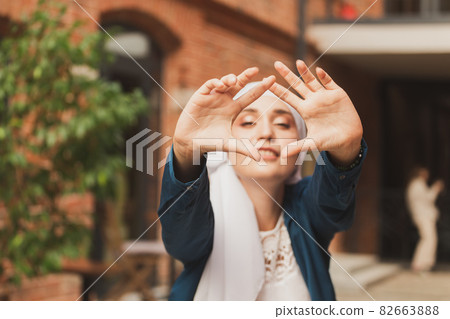 Portrait of young muslim woman wearing hijab head scarf in city while looking at camera. Closeup face of cheerful woman covered with headscarf smiling outdoor. Islamic girl outdoors. Portrait of young muslim woman wearing hijab head scarf in city while looking at camera. Closeup face of cheerful woman covered with headscarf smiling outdoor. Islamic girl outdoors. 82663888