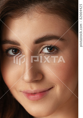 Close-up portrait of young beautiful girl without makeup isolated over dark studio background. Natural beauty concept. Close-up portrait of young beautiful girl without makeup isolated over dark studio background. Natural beauty concept. 82664425