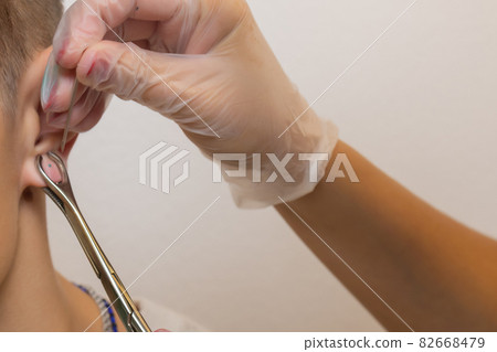 Professional holding the jewel of piercing just before screw the ball. 82668479