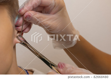 Professional holding the jewel of piercing just before screw the ball. 82668480