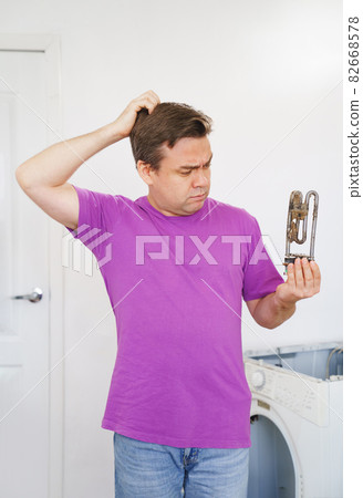 sad repairman of washing machine holds old tubular electric heater sad repairman of washing machine holds old tubular electric heater 82668578