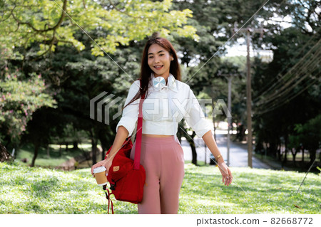 Portrait asian woman with headset hand holding a cup of coffee in ter garden 82668772