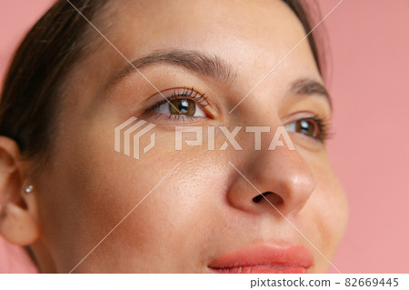 Close-up portrait of young beautiful girl without makeup isolated over pink studio background. Natural beauty concept. Close-up portrait of young beautiful girl without makeup isolated over pink studio background. Natural beauty concept. 82669445