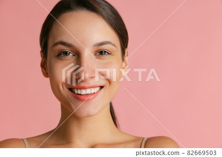 Close-up portrait of young beautiful girl without makeup isolated over pink studio background. Natural beauty concept. Close-up portrait of young beautiful girl without makeup isolated over pink studio background. Natural beauty concept. 82669503