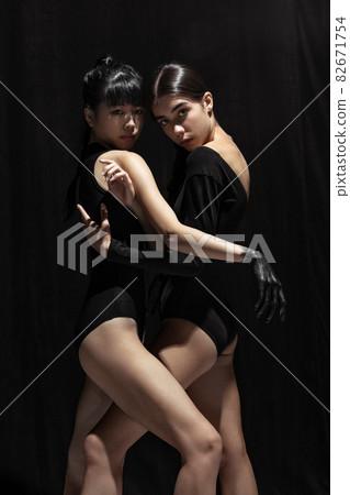 Modern ballet performance. Two beautiful girls, modern dancers in art performance isolated on dark background. Feelings, emotions concept Modern ballet performance. Two beautiful girls, modern dancers in art performance isolated on dark background. Feelings, emotions concept 82671754