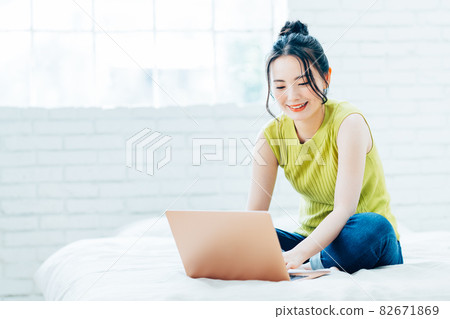 在臥室裡看電腦的年輕女人 82671869