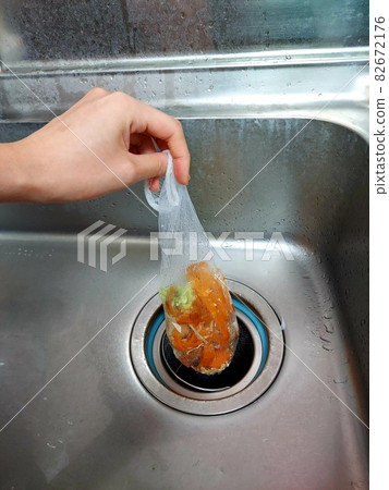 Hand holding kitchen waste collected in the drain of the sink Hand holding kitchen waste collected in the drain of the sink 82672176