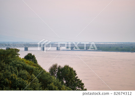 Khabarovsk, Russia - Aug, 14, 2021: Bridge over the Amur River in Khabarovsk, Russia. Evening photography. Khabarovsk, Russia - Aug, 14, 2021: Bridge over the Amur River in Khabarovsk, Russia. Evening photography. 82674312