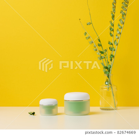 green jar for cosmetics on a white table. Packaging for cream, gel, serum, advertising and product promotion green jar for cosmetics on a white table. Packaging for cream, gel, serum, advertising and product promotion 82674669
