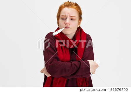 Cropped portrait of young Caucasian girl having cold and flue, measuring temperature isolated over white background Cropped portrait of young Caucasian girl having cold and flue, measuring temperature isolated over white background 82676700