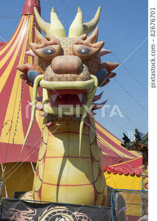 The figure of an inflatable dragon on the background of the circus domes. Russia, Krasnoyarsk July 2021. The figure of an inflatable dragon on the background of the circus domes. Russia, Krasnoyarsk July 2021. 82676701