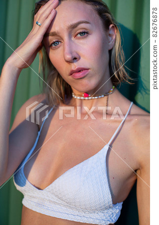 Girl with blonde hair with green fence behind Girl with blonde hair with green fence behind 82676878