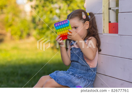 Child playing with pop it,pressing the bubbles with his fingers,top view.New antistress toy for children and adult.Copy space for text or design. 82677761