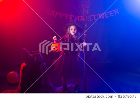 Little girl holds pumpkin jack on Halloween holiday. Kid girl wear witch costume. Fantasy, fairy tale and masquerade concept. 82679575