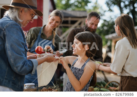 Little girl buying organic vegetables outdoors at community farmers market. Little girl buying organic vegetables outdoors at community farmers market. 82679986