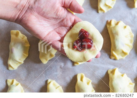 Making dumplings filled with sour cherry with sugar Making dumplings filled with sour cherry with sugar 82680247