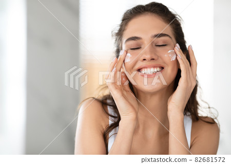 Lady Applying Facial Cream On Cheeks With Eyes Closed Indoor Lady Applying Facial Cream On Cheeks With Eyes Closed Indoor 82681572