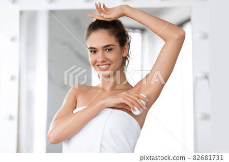 Young Female Applying Antiperspirant Smiling To Camera In Bathroom 82681731