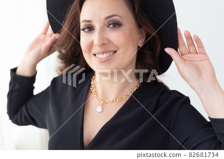 Close-up portrait of a beautiful graceful woman in elegant hat with a wide brim. Beauty and fashion concept. 82681734