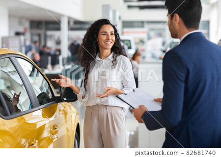 Pretty lady having conversation with sales assistant in showroom 82681740