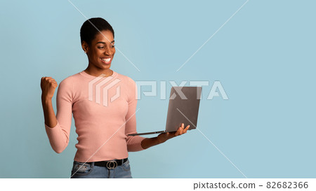 Joyful Black Woman Celebrating Success With Laptop, Raising Clenched Fist With Excitement 82682366