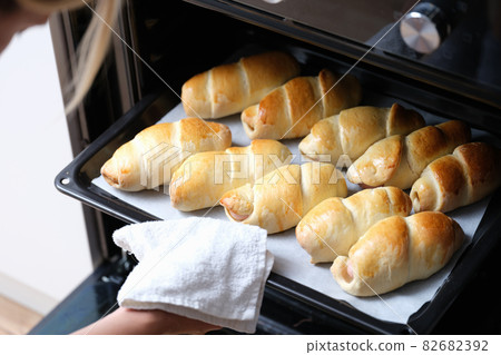 Woman chef taking out baking sheet with delicious buns from oven closeup 82682392