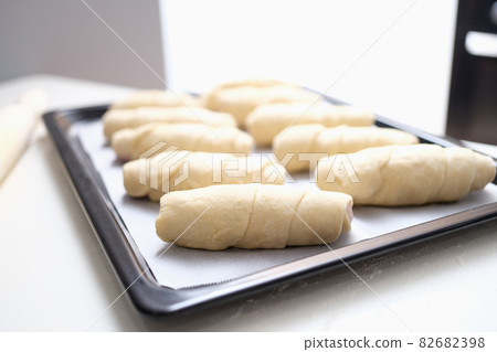 Lots of uncooked puff pastry buns on baking sheet closeup Lots of uncooked puff pastry buns on baking sheet closeup 82682398
