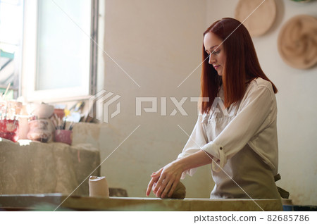 Ginger cute potter working in her workshop and looking involved 82685786