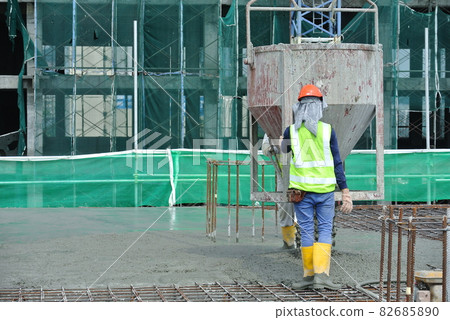 KUALA LUMPUR, MALAYSIA -AUGUST 8, 2018: Group of construction workers pouring wet concrete using the mobile crane bucket at the construction site. KUALA LUMPUR, MALAYSIA -AUGUST 8, 2018: Group of construction workers pouring wet concrete using the mobile crane bucket at the construction site. 82685890