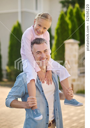 Little girl sitting on daddys shoulders Little girl sitting on daddys shoulders 82686220