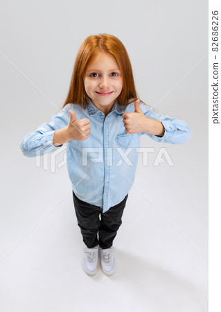 Top view portrait of little Caucasian girl, child posing isolated over white studio background. Thumbs up. Delightful 82686226