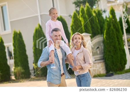 Man holding daughter on his shoulders and wife Man holding daughter on his shoulders and wife 82686230