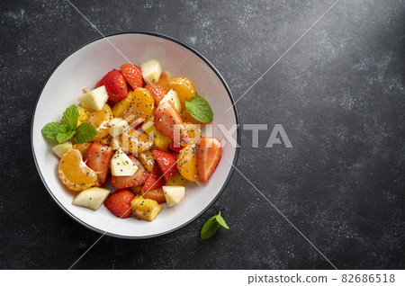 Fruit salad with fresh apple, strawberry, tangerines, pineapple and honey. Copy space. Fruit salad with fresh apple, strawberry, tangerines, pineapple and honey. Copy space. 82686518