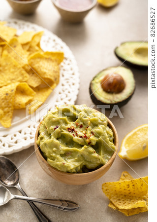Guacamole dip with corn chips - nachos on bright background, party food Guacamole dip with corn chips - nachos on bright background, party food 82686527