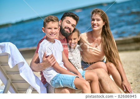 A happy family spending time near the water and looking relaxed 82686945