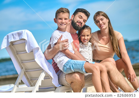 A happy family spending time near the water and looking relaxed 82686953