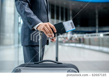 Mans hand with ticket touching handle of suitcase Mans hand with ticket touching handle of suitcase 82687185