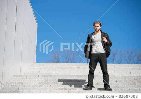 thoughtful young man sitting on steps against blue sky background thoughtful young man sitting on steps against blue sky background 82687308