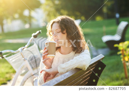 Pretty young girl having coffee in the park in the morning 82687705