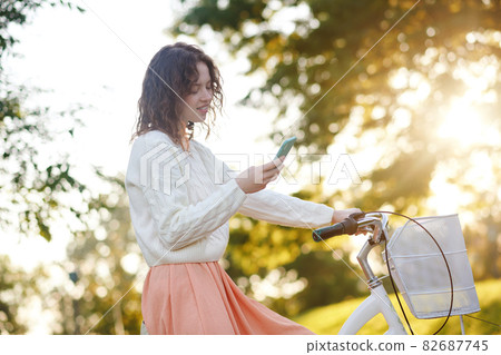 A young girl in a park with a smartphone in hands 82687745