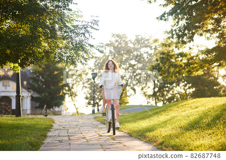A young girl riding a bike in sunlight in the park 82687748