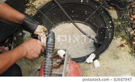 Drain cleaning. Plumber repairing clogged grease trap with auger machine. Maintenance the sewage system and grease trap by professional plumber. Using auger snake to fix and unclog a drain. Drain cleaning. Plumber repairing clogged grease trap with auger machine. Maintenance the sewage system and grease trap by professional plumber. Using auger snake to fix and unclog a drain. 82687847