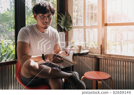 Man drink coffee and reading book in warm light summer. 82689149