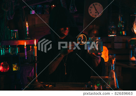 sorcerer alchemist in dark clothes is engaged in potion making in a craft workshop 82689663