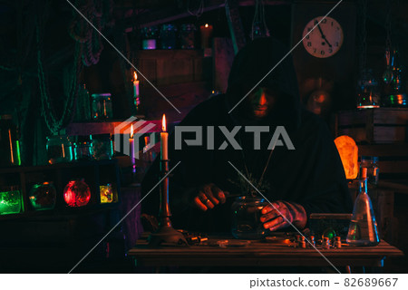 alchemist magician sorcerer does experiments with a potion in a laboratory 82689667